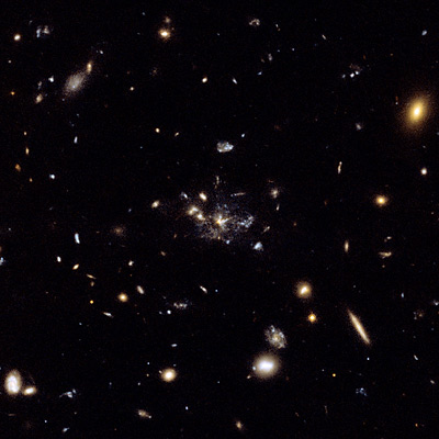 FIGURA 2: Ejemplo de fusión galáctica en una galaxia distante. Varias decenas de objetos están uniéndose para dar al final una elíptica como la de la Figura 1. En el proceso se forman estrellas nuevas que se concentran en brotes (en azul en la imagen). 
